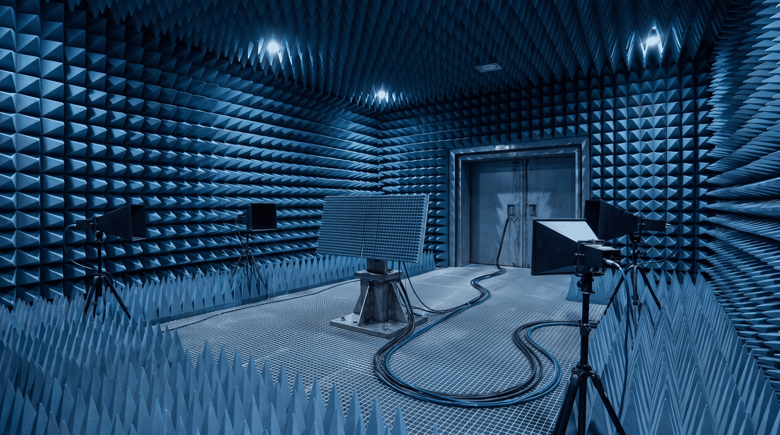 Illustration: an anechoic chamber with a receive array on a positioner and four horn antennas on stands around it.